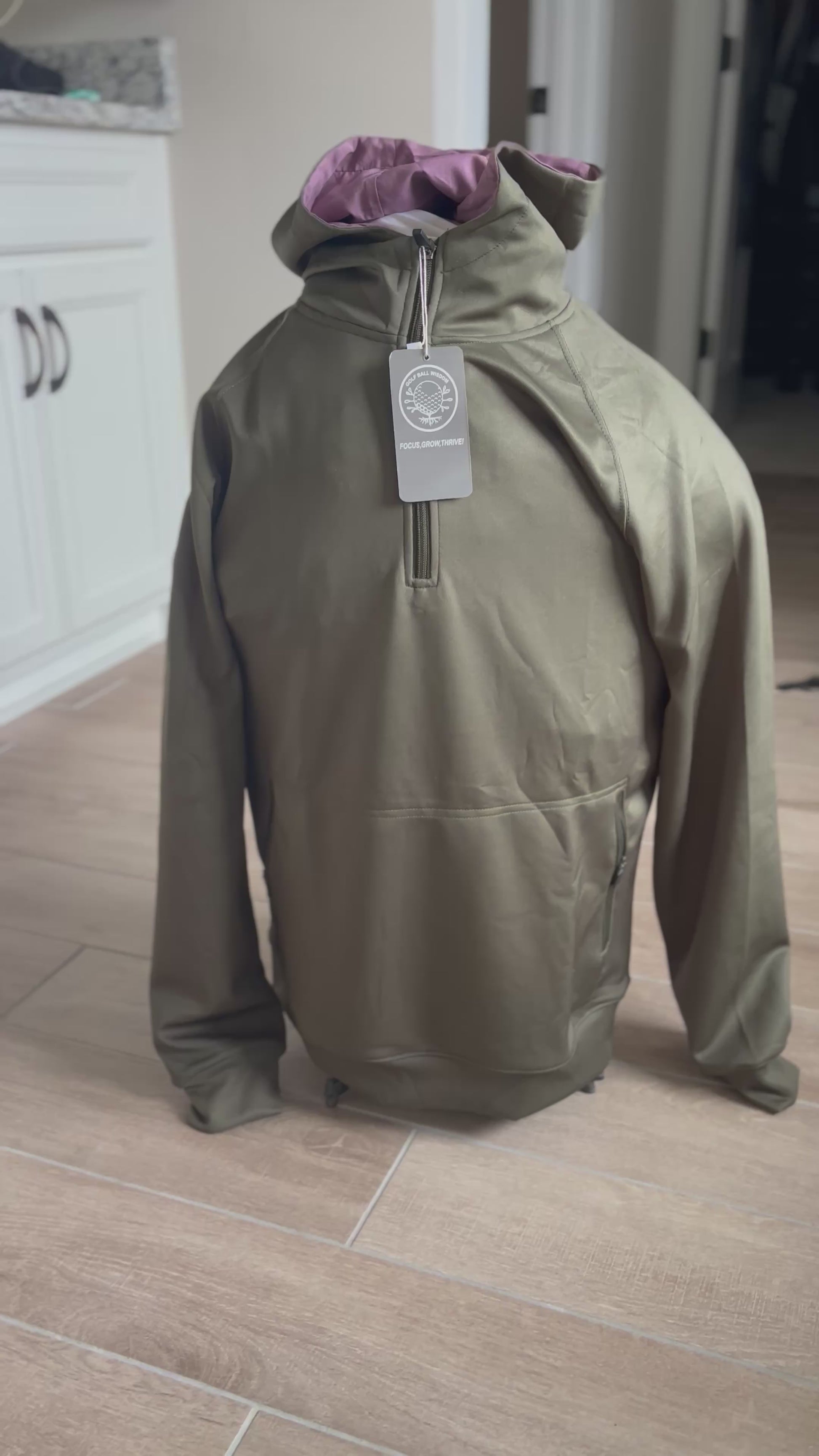 Army green performance hoodie with black half-zip and vertical pockets – Golf Ball Wisdom’s limited Ruck Hoodie supporting teen mentorship